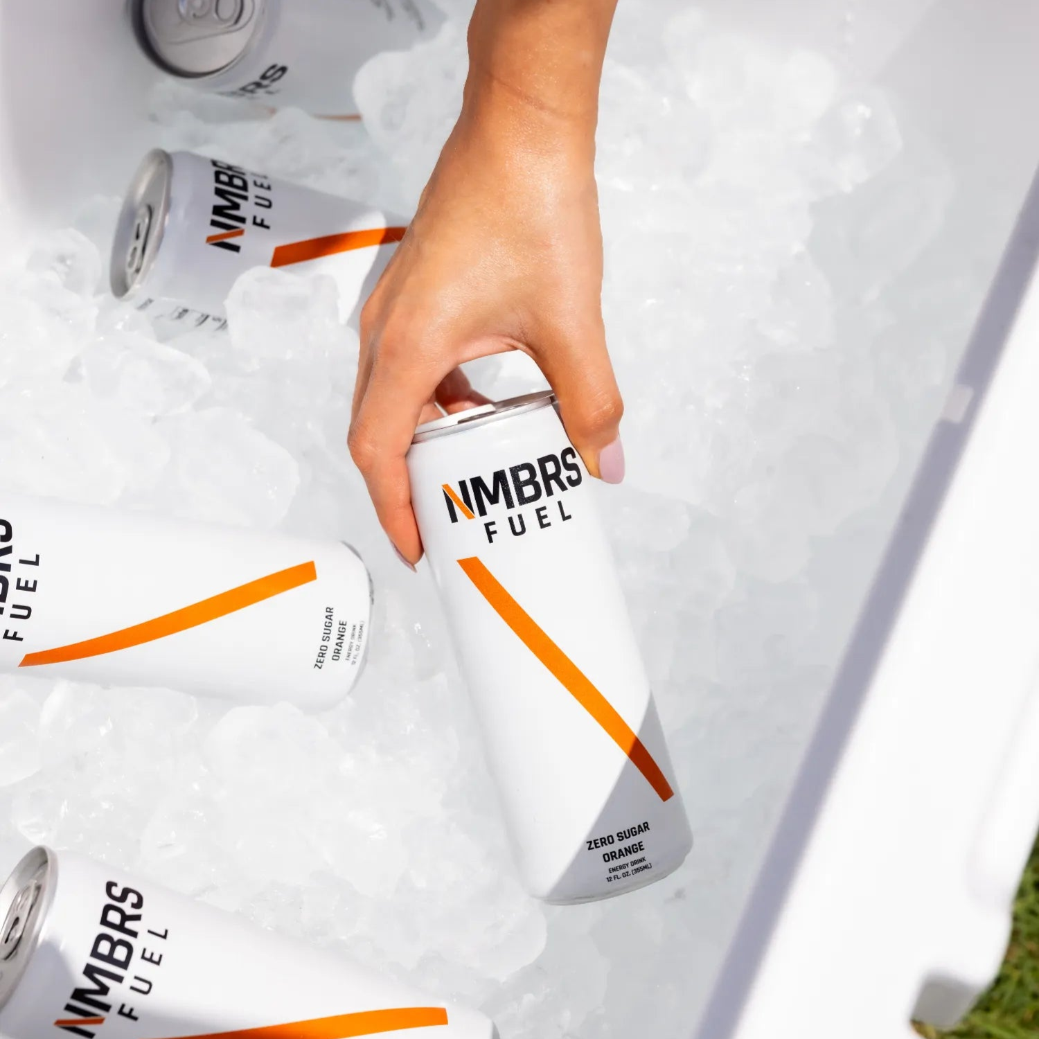 Hand reaching for a can of NMBRS Fuel from an ice-filled cooler.
