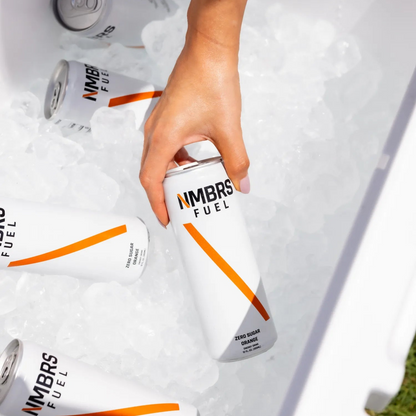 Hand reaching for a can of NMBRS Fuel from an ice-filled cooler.