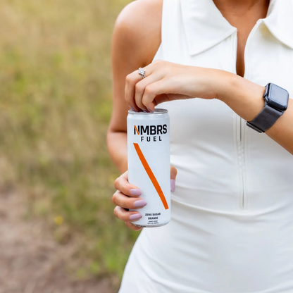 Person holding a can of NMBRS Fuel in an outdoor setting